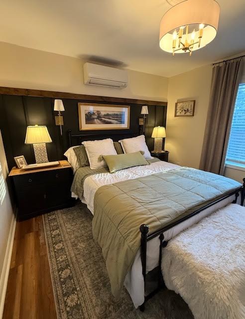 Bedroom with a dark green accent wall and brass sconces