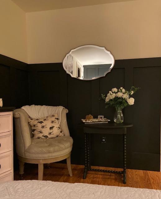 Bedroom corner with black board and batten, a tufted armchair, and an oval mirror